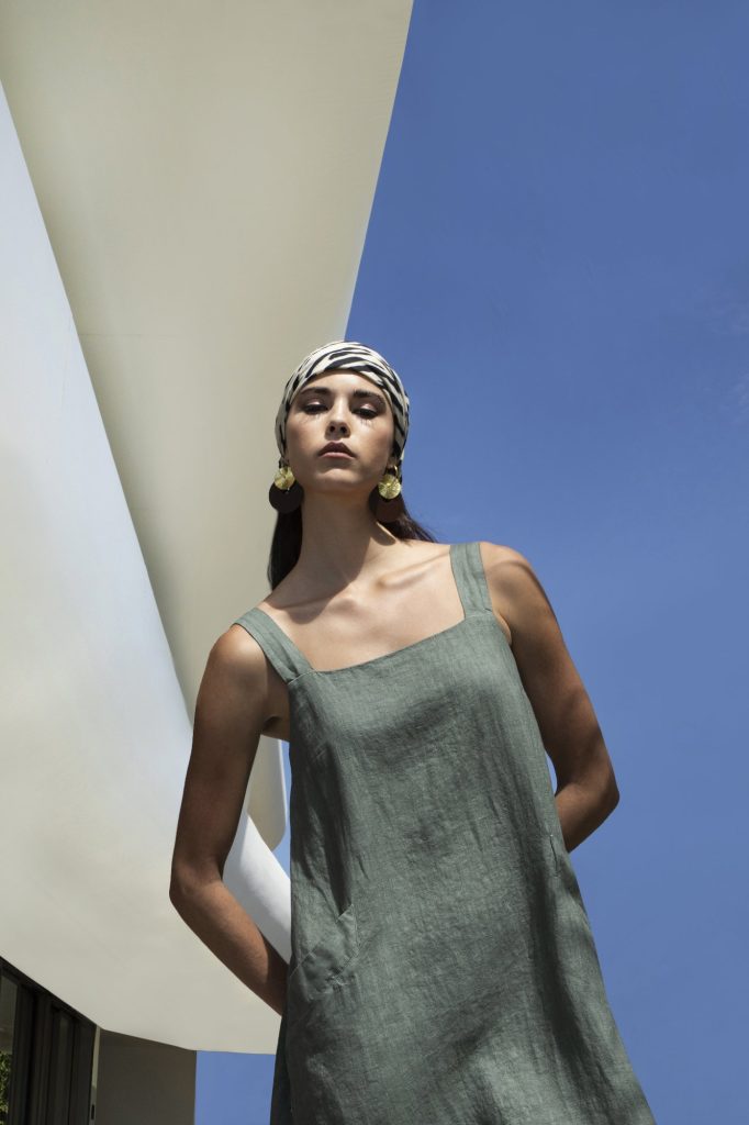 Woman in a sage linen dress against a blue sky