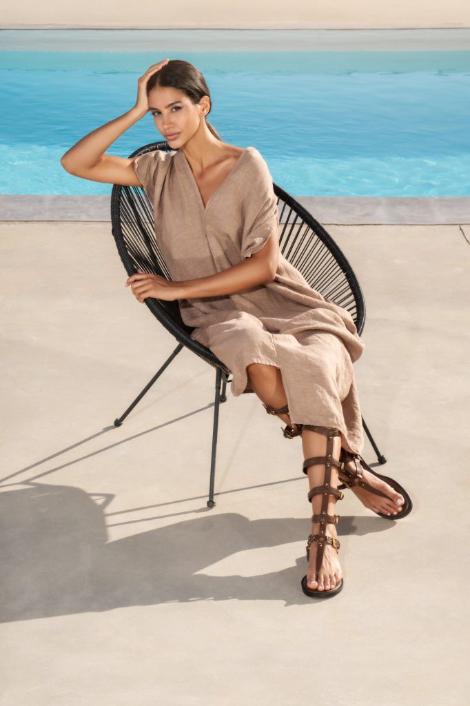 Woman in a beige linen dress sitting by the pool